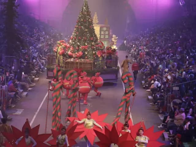O Grande Desfile de Natal reúne artistas fantasiados diante de uma árvore iluminada